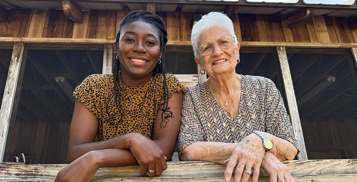Two women standing on a porch smiling 