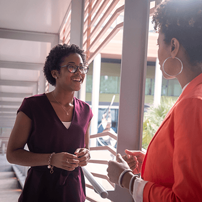 A student smiling while talking to a professor.