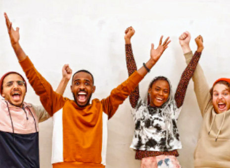 Four people raise their hands in excitement.