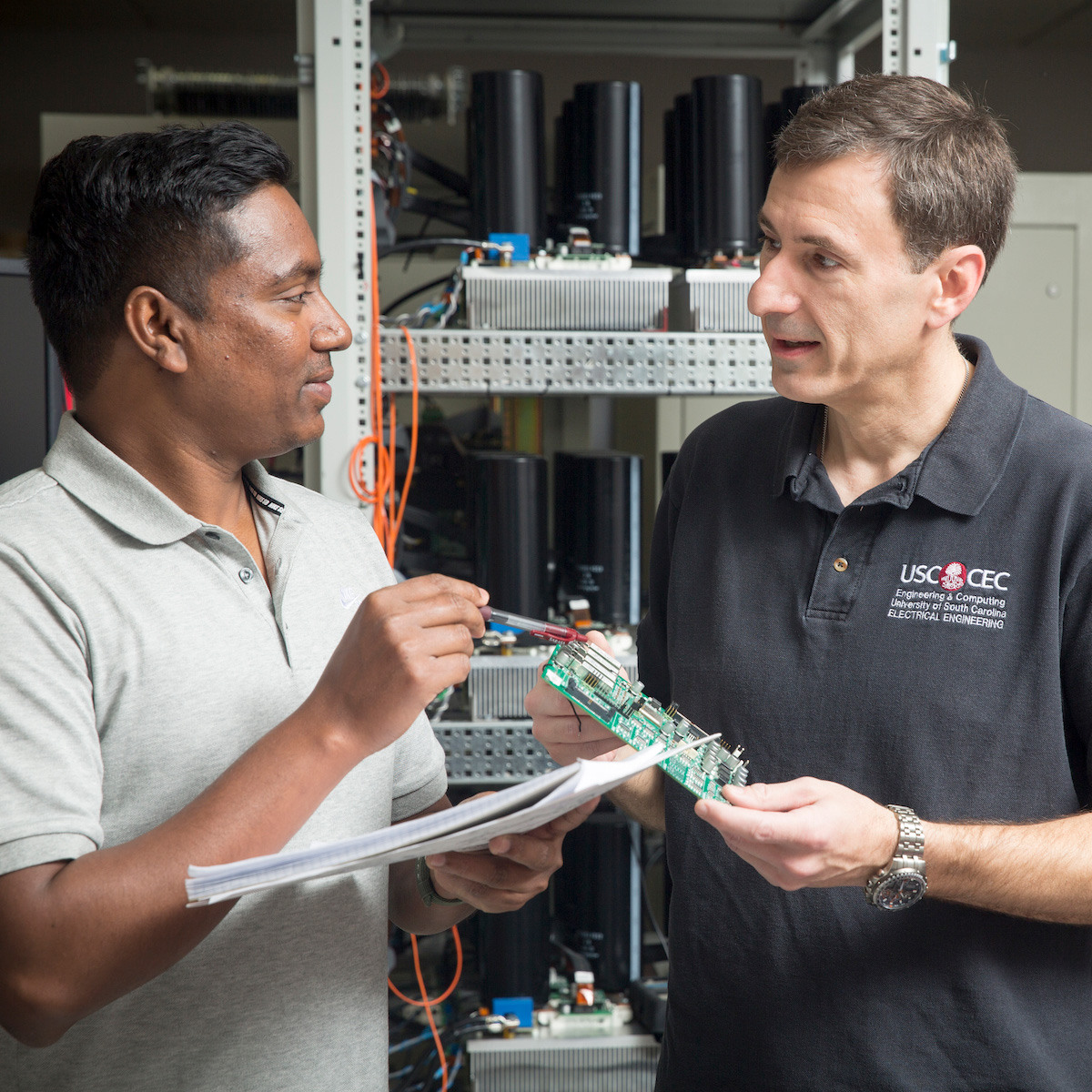 A student and CEC instructor discuss a circuit board.