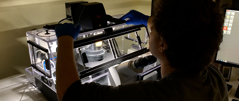 a reseracher sitting at a microscope 