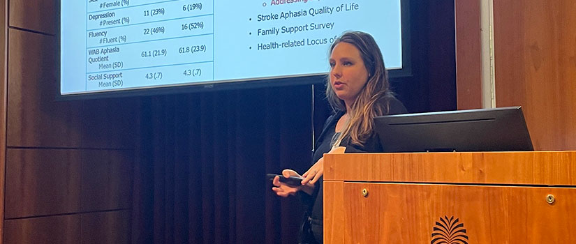 woman with dark hair and suit presenting a powerpoint 