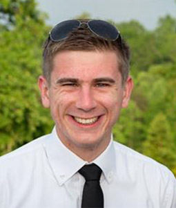 man with white shirt and tie on smiling outside 