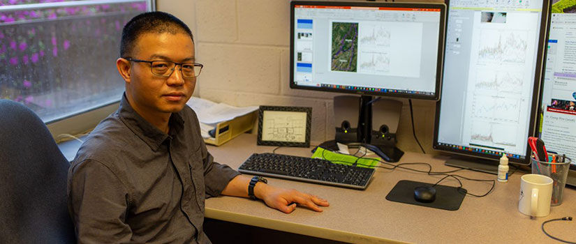 Photo of Huan Ning sitting at his desk. 