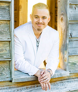 Henry Tran, Ph.D. leaning out the window of a log cabin