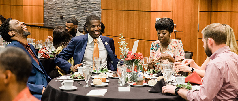 a diverse group of formally-dressed people around a table