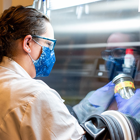 a graduate student works with radioactive materials under a hood