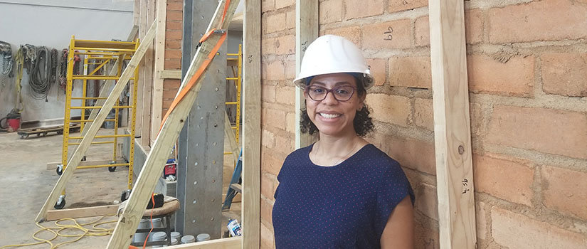 Doctoral candidate Erika Rengifo-Lopez in front of walls made of plastic-reinforcement bricks.