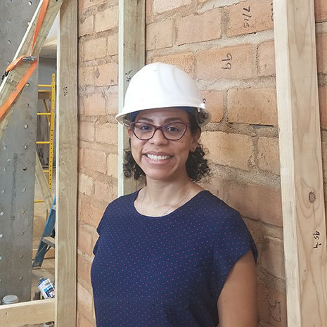 Heashot of Lopez wearing a construction hat in front of a wall