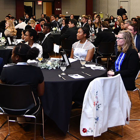 Students sitting at tables in a ballroom