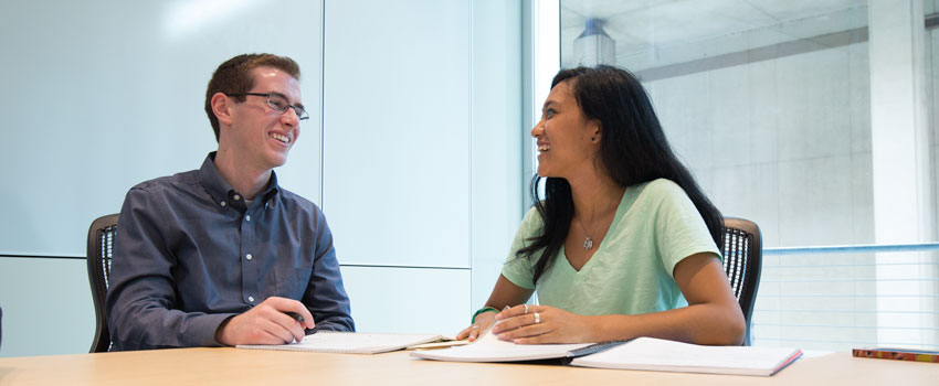 A student and an advisor work together at a table.