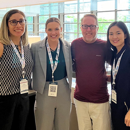 Four people attending a research conference pose for a photo.