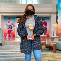 Alexandria Hill stands holding a trophy in the NFL Club