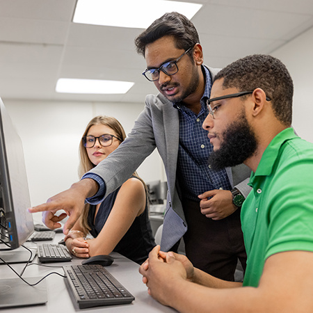 A faculty member instructs two students on a computer