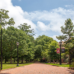 the entrance to the historic horseshoe, with the gates open and the brick walkway leading in.