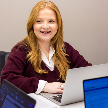 student in front out a laptop smiling with a group