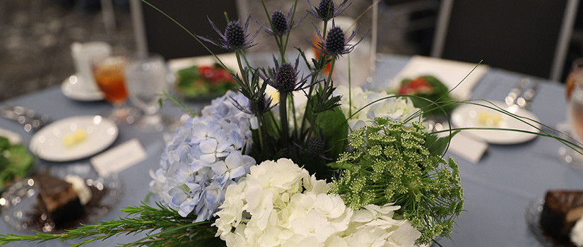 Table layout with flower centerpiece, plates, napkins, drinkware and silverware