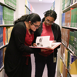 Students looking at a book in the library