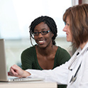 two women, one black, one white working on a laptop