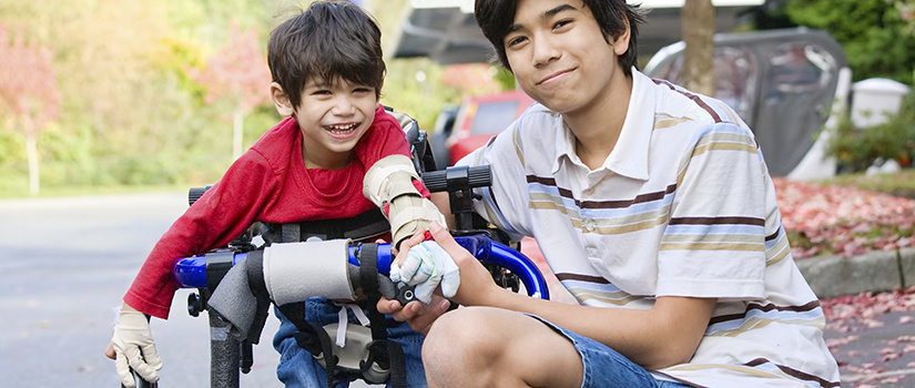 Older brother with younger brother who is in an assistive walker.