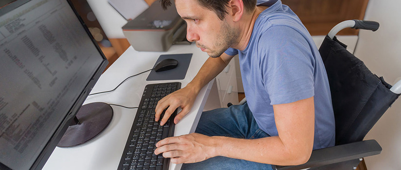 A man in a wheelchair uses a computer