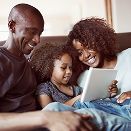 mother and father with child looking at tablet device.