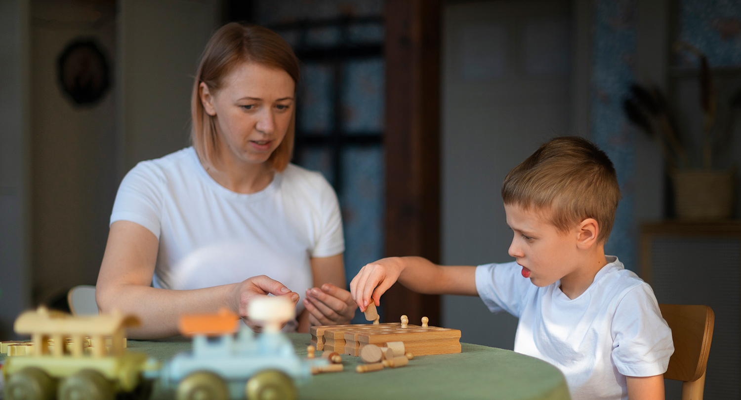 Mother plays tabletop game with young son.