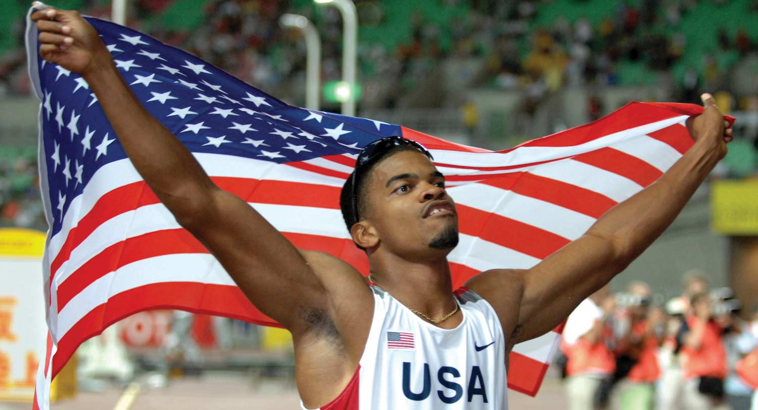 Hurdler Terrence Tramill holds U.S. flag honoring his silver medal