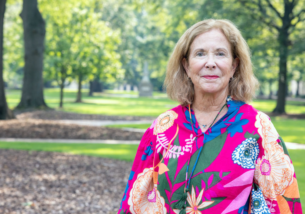 woman stands outside with grass and trees in the background