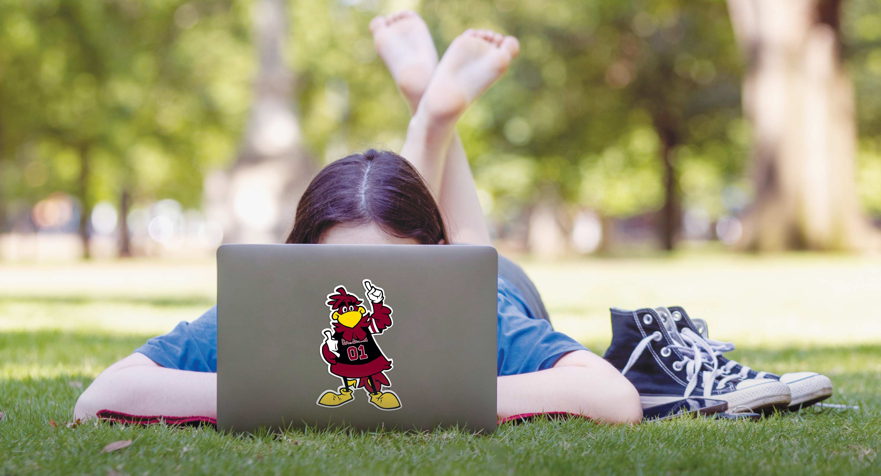 A student lounges on the Horseshoe with her laptop computer.