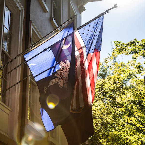south carolina and american flag hanging next to beige building