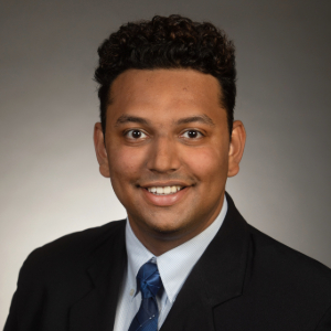 head and shoulders photo of a man in a suit with gray background