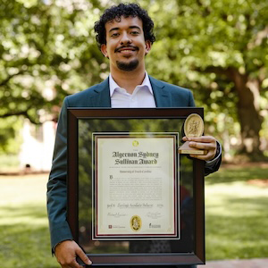 man in white shirt and blue suit holding framed award