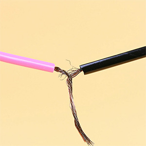 A pink wire (left) is joined with a black wire by twisting inside wiring together